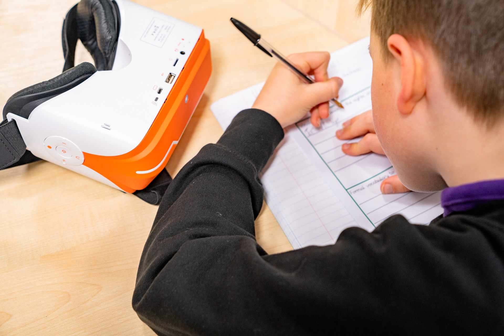 A child with a VR headset writing.